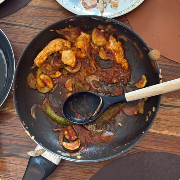 Een foto van een pan met restjes in tomatensaus.